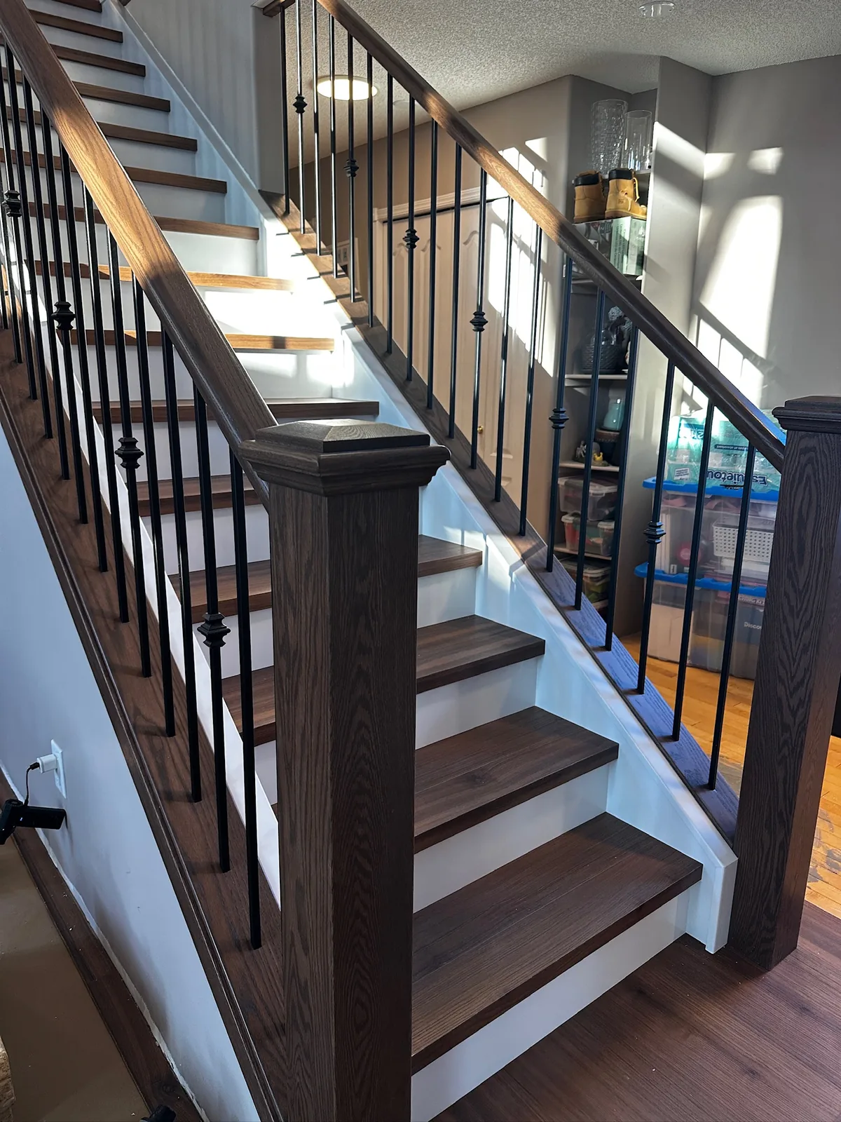 Dark stained oak railing with knuckle detail spindles beside a walnut toned hardwood staircase