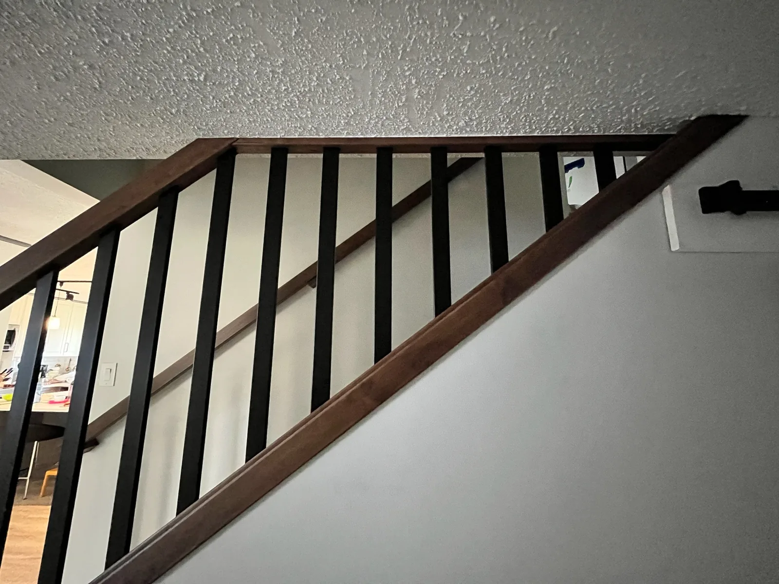Walnut stained handrail with black metal spindles seen from below on an upper landing