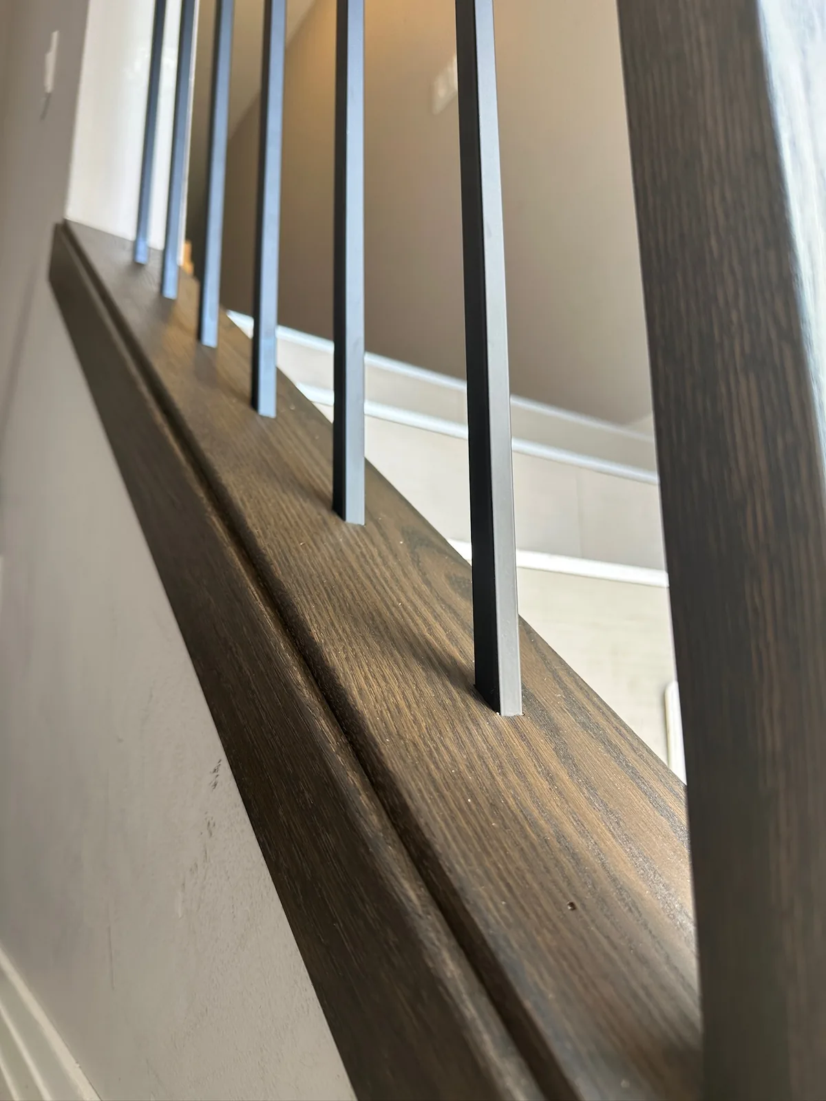 Close view of a dark stained handrail with alternating black and white spindles