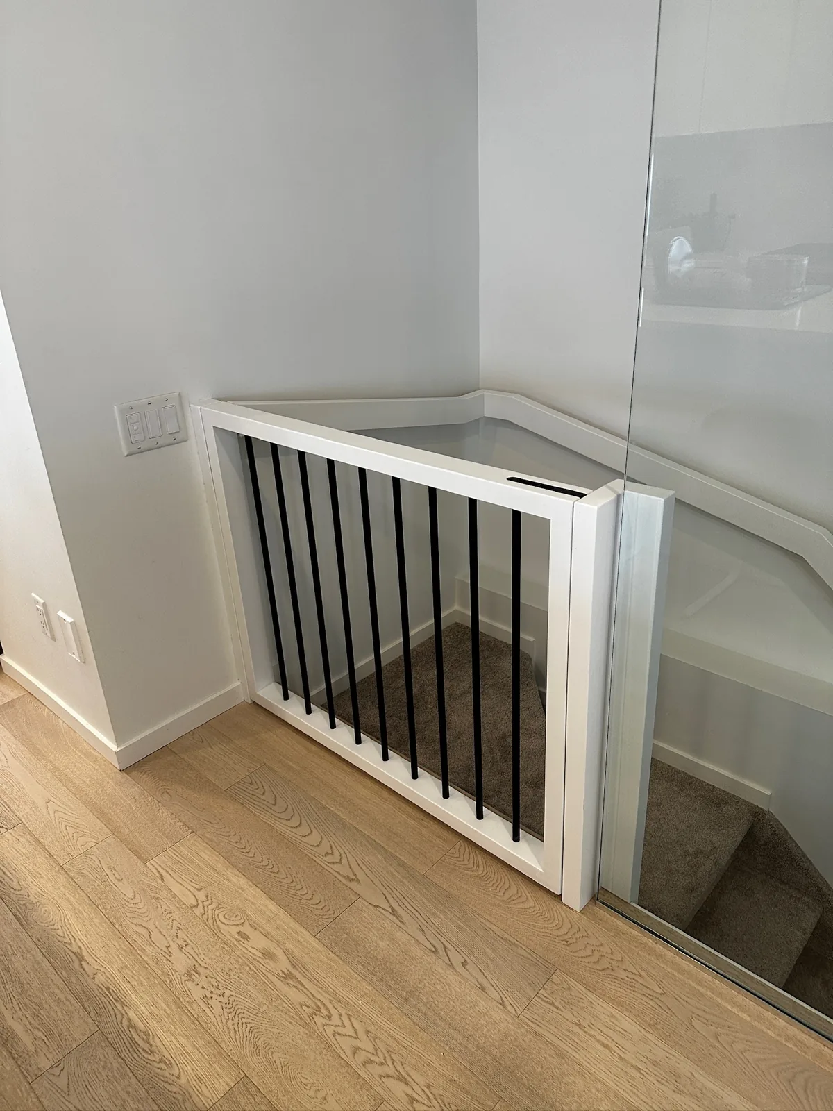 White painted railing with black metal spindles at the top of a carpeted basement stair