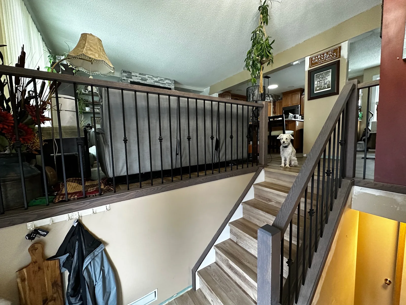 Grey stained railing with black spindles overlooking an open plan kitchen and living room