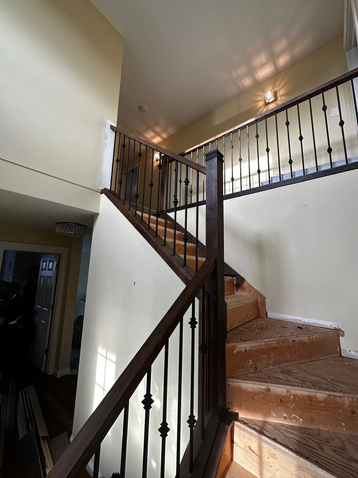 Dark stained newel post and knuckle spindles on a staircase with bare pine treads mid build