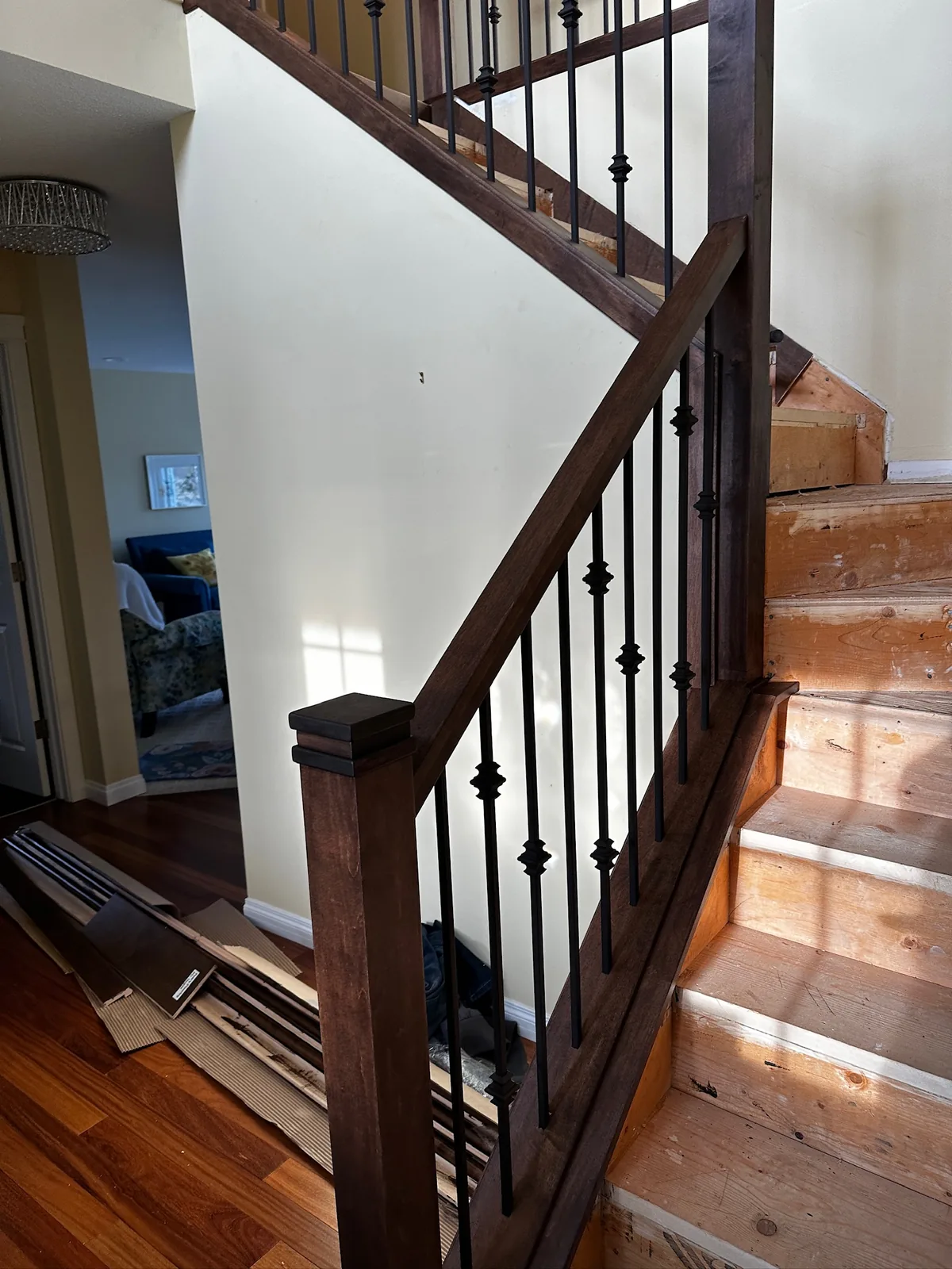Dark stained oak railing with black knuckle spindles over unfinished stair treads