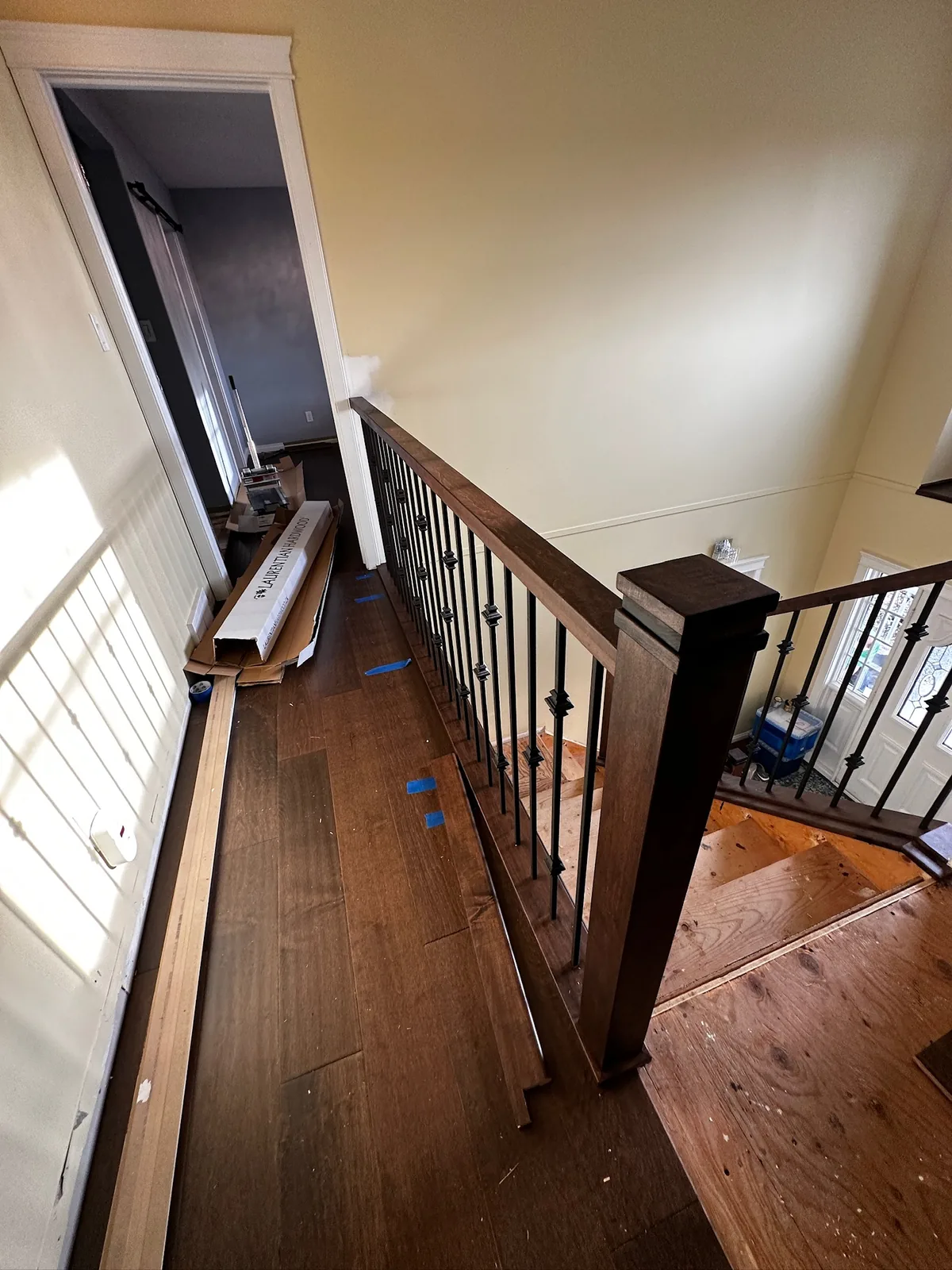 Dark stained handrail and black spindles along an upper hallway during a flooring renovation