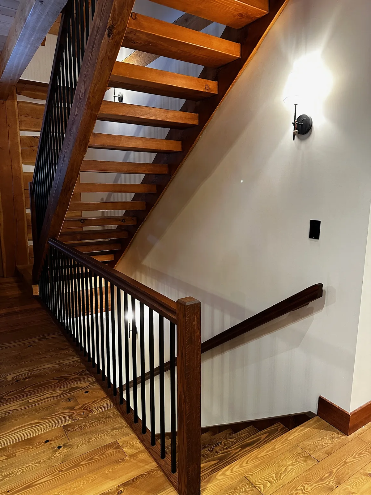 Open riser staircase with timber treads and a dark stained railing with black spindles