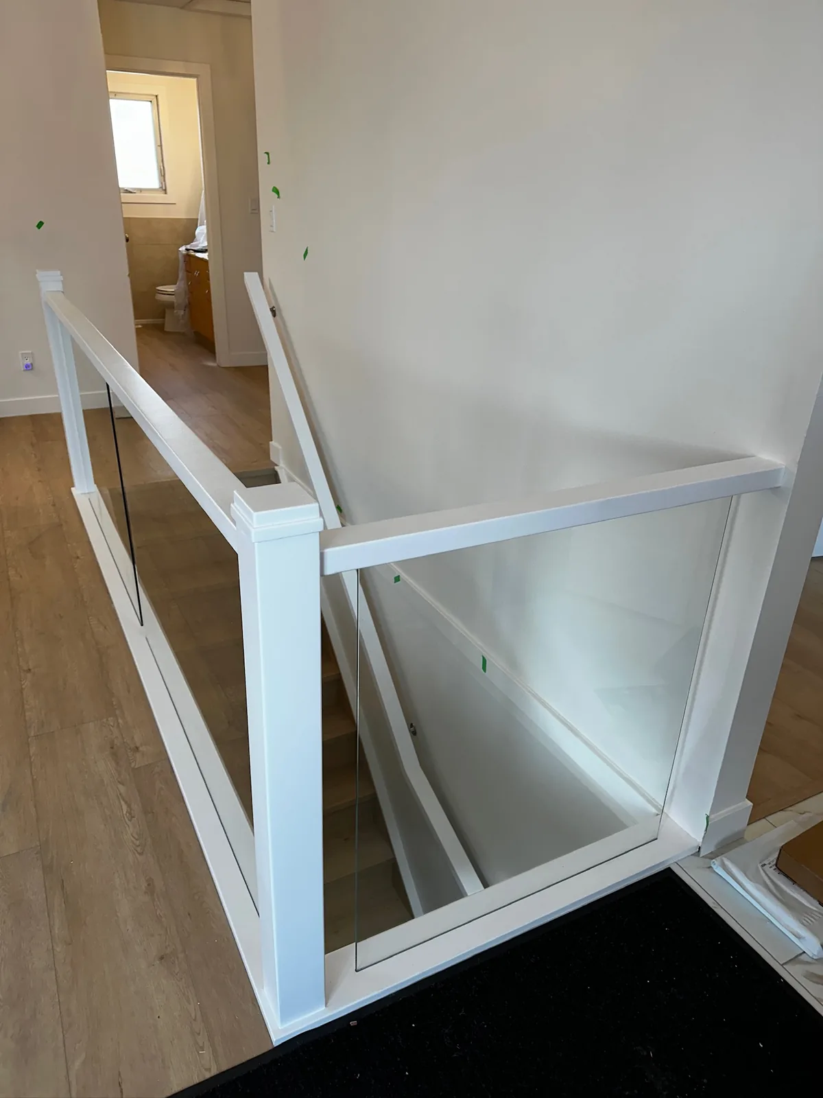 White painted post and rail with tempered glass panels beside a wood floor