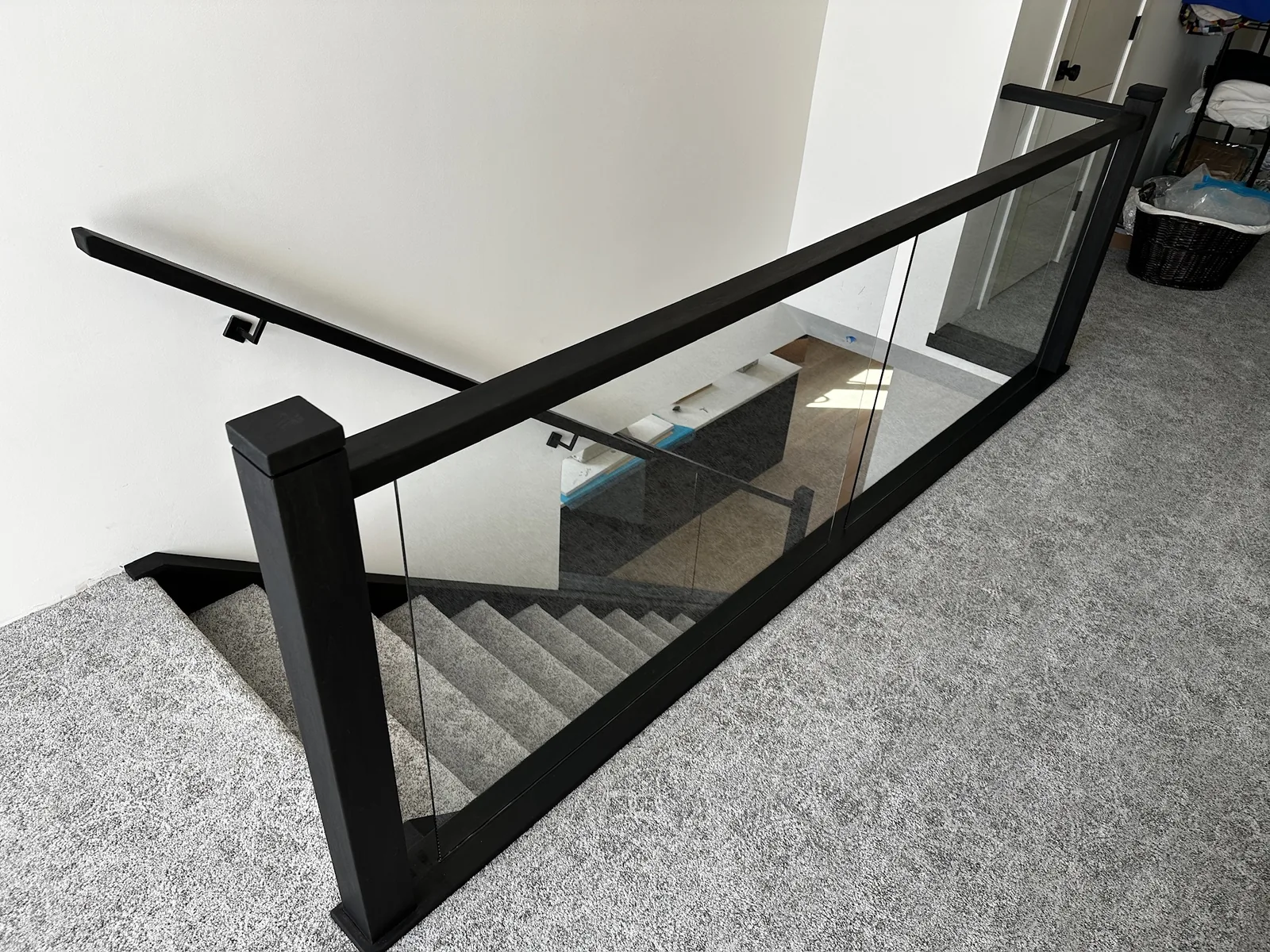 Black framed glass railing around a carpeted landing