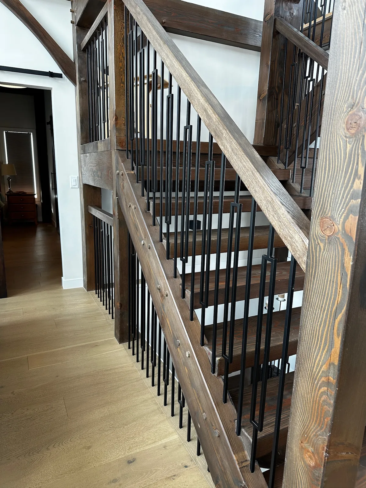 Reclaimed timber posts and rail with slim black spindles on an open staircase