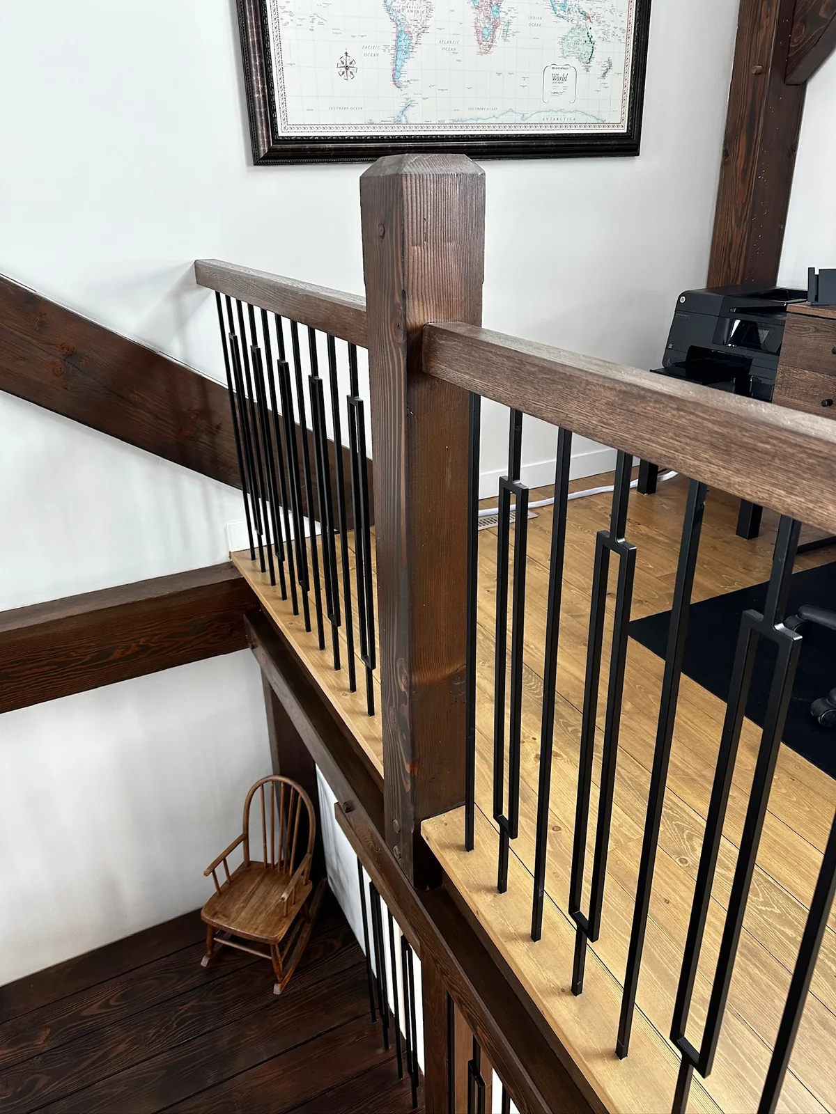 Rough sawn timber rail and post with black spindles above a dark stained floor