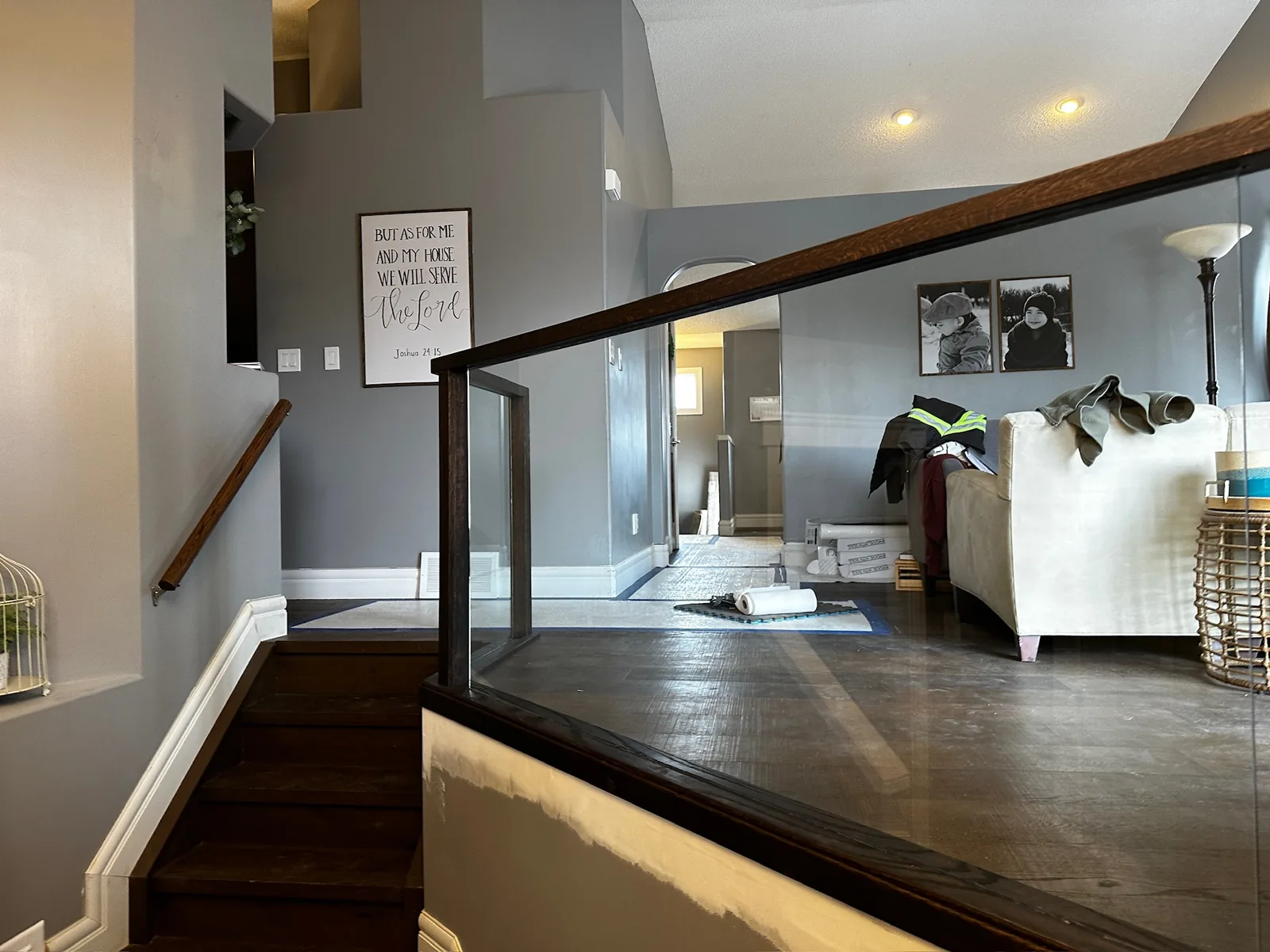 Wood and glass railing along a landing above a stained hardwood floor