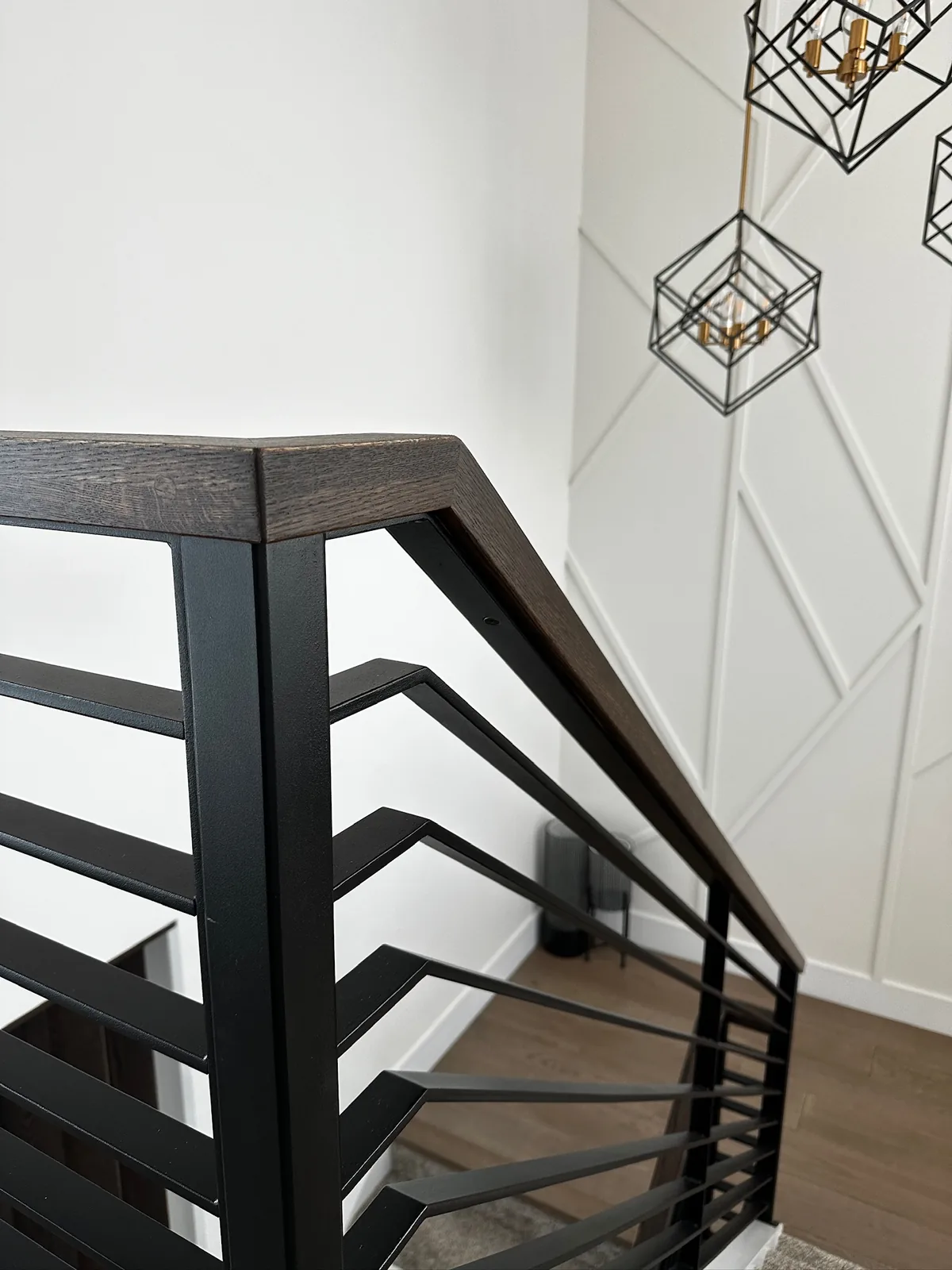 Black metal railing with flat horizontal bars and a dark stained wood cap