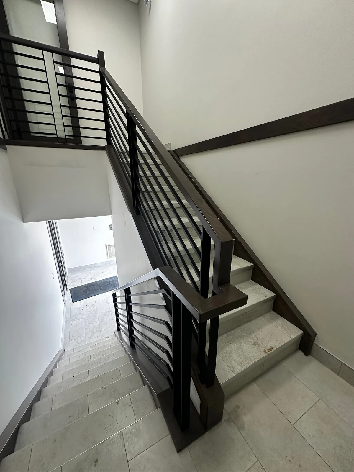 Black horizontal bar railing on a staircase with tile treads in a home under construction