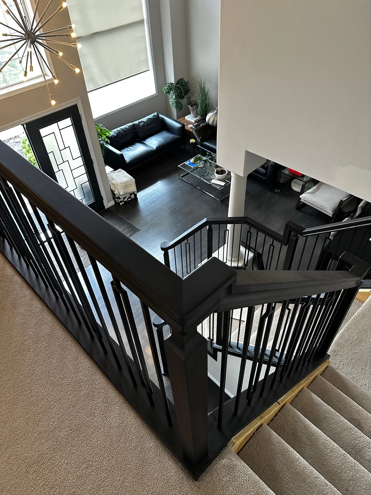 Black stained railing with square spindles around a carpeted upper landing