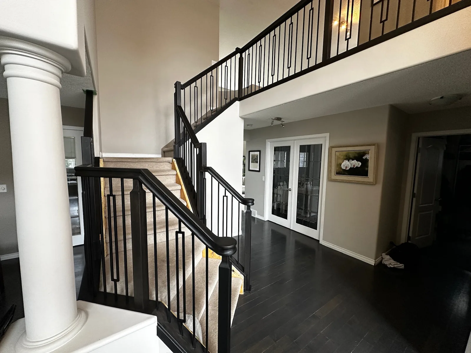Black stained curved staircase railing with decorative spindles in a two storey entry